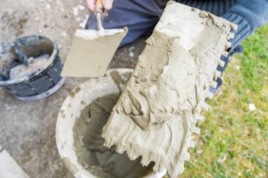 Ev tadilatı, tadilat, inşaat alanında çimento harcı olan bir kova malayla el ele tutuşmak. Yüksek kalite fotoğraf