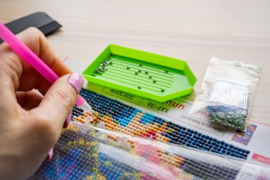 Bir kadın boncuklu bir resim çiziyor. Boncuklardan yapılmış bir dizi resim. Hobiler, el sanatları için. Rahatlama. Yüksek kalite fotoğraf