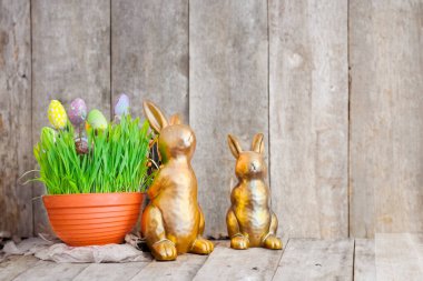 Çiçek açan bahar çiçekleri ahşap bir rafta duruyor, dekoratif tavşan heykelciklerinin önü, bir metin için kopyalama alanı. Paskalya Kutlaması Konsepti. Yüksek kalite fotoğraf