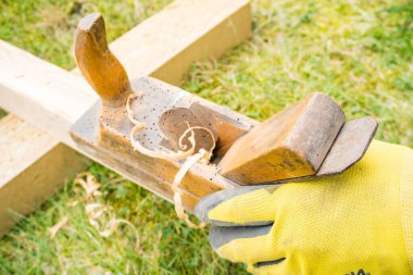 Yatay, yüksek açılı, küçük, klasik ahşap planörlü bir stüdyo çekimi. Üzerinde tahta solucan delikleri olan eski bir marangoz aleti. İnce ahşap talaşı. Marangozluk konsepti. Yüksek kalite fotoğraf