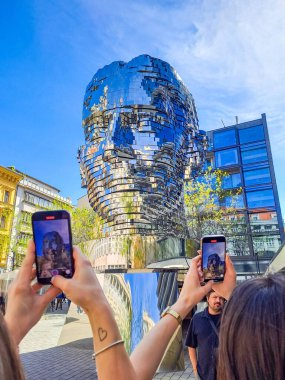Prague- Czech- 12 april 2024: Statue of Franz Kafka, the latest work by artist David Cerny is located at yard of the shopping center Quadrio. Tourists film on their phones how the statue spins  clipart