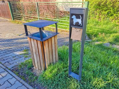 Hlasna Treban- Çek - 21 Nisan 2024: Köpek atıkları için kağıt torba dağıtıcısı, ahşap ve demirden yapılmış modern bir çöp tenekesinin yanında. Yüksek kalite fotoğraf