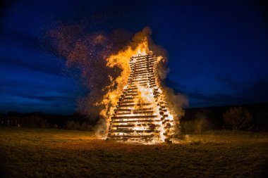 Bir cadının yanması. 30 Nisan 'da Çek Cumhuriyeti' nde tatil. Revnice. Ateş siyah arkaplanda parçacıkları kor haline getirir. Yangın arka plan kıvılcımları. Soyut koyu parıltılı ateş parçacıkları ışıkları.