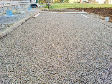 Evin avlusundaki verandaya gri beton döşeme döşemesi. Profesyonel işçiler yeni fayanslar veya levhalar döşüyorlar Seviyeli kum temeli üzerine garaj yolu, kaldırım veya veranda için.