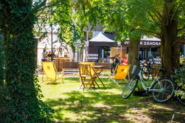 Podebradi- Çek- 27 Temmuz 2024: İnsanlar ağaçların gölgesindeki sıcaktan ve su damlalarından, Central Park 'taki çeşmeden kaçıyorlar. Yüksek kalite fotoğraf