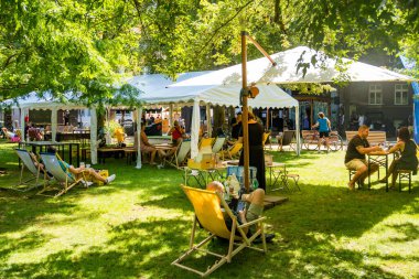 Podebradi- Çek- 27 Temmuz 2024: İnsanlar ağaçların gölgesindeki sıcaktan ve su damlalarından, Central Park 'taki çeşmeden kaçıyorlar. Yüksek kalite fotoğraf