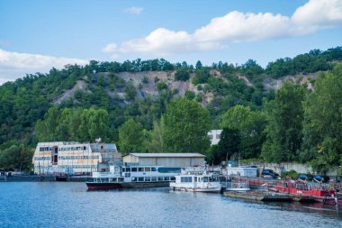 Prague- Czech- 5 August 2024: A narrowboats and houseboats on the river Vltava which runs through the city center and used for boating. New Eco Modern Residential Housing. High quality photo clipart