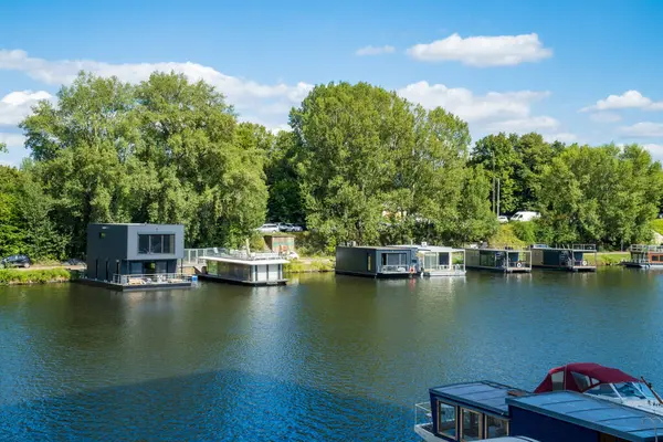 stock image Prague- Czech- 5 August 2024: A narrowboats and houseboats on the river Vltava which runs through the city center and used for boating. New Eco Modern Residential Housing. High quality photo