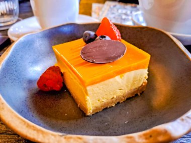 Üzerinde parlak kırmızı çilek, ahududu ve çikolatalı yaban mersini olan çürümüş mango peynirli kek. kopyalama alanı. Yüksek kalite fotoğraf