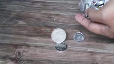 Birisi onun elinden yere gümüş para yığını koyuyor.