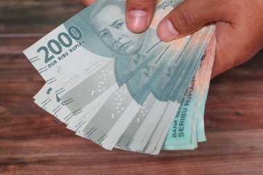 2000 senelik Endonezya Rupisi 'ni iki elini de kullanarak kapat.