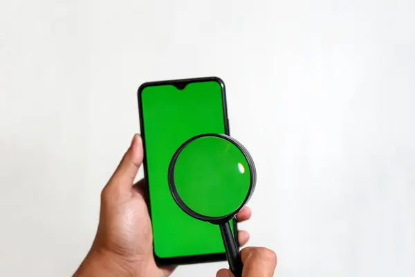 Yeşil ekranlı akıllı telefonları tutan ellerin kapatılması ve beyaz arkaplanda izole edilmiş büyüteç kullanarak daha yakın ekran noktaları gösterilmesi, medya aktarım veri dosyalarını paylaşan kişi