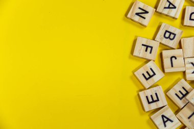 Kenarları ahşap alfabeyle çevrili güzel, parlak, sarı bir arka plan ve negatif bir boşluk. 