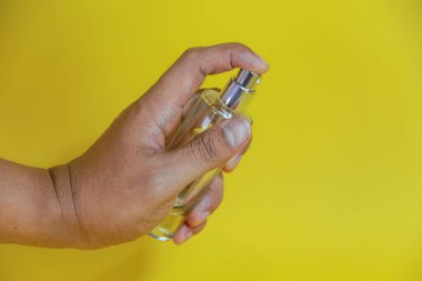 Sarı arka planda el yapımı parfüm şişesi.