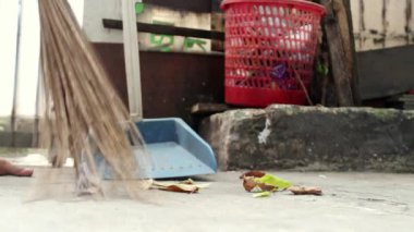 Adam süpürge sopasıyla evin bahçesini çöpten temizliyor.