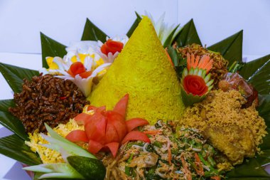 Tumpeng pilavı. Etrafında çeşitli mezeler var. Tipik Endonezya koni şeklinde pirinç yemeği.