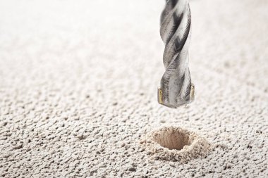 Metal matkap ucu, endüstriyel sondaj makinesinde talaşlarla beton duvarda delikler açar. Metal iş endüstrisi