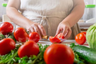 Şef restoranda domatesleri bıçakla dilimliyor. Mutfakta kesim ve hazırlama işlemi.