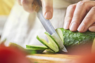 Restoranda masada salatalık dilimleyen şef. Mutfakta sebze doğrama işlemi.