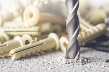 Metal matkap ucu, beton duvarda plastik kaplama ve duvar tıkaçlarıyla delikler açar. Çalışma endüstrisi inşa ediliyor.