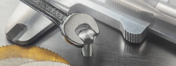 Wrench tightens bolt in steel plate with ruler and caliper. Spanner, bolt, screw and nuts.