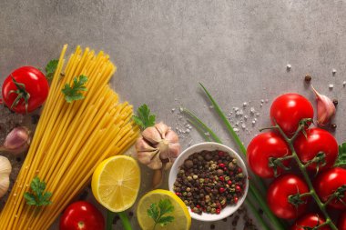 Taş masanın üzerinde İtalyan yemekleri var. Makarna, fesleğen ve sebze..