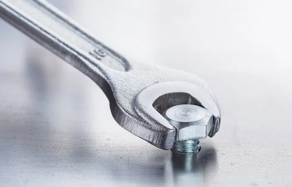 stock image Wrench tightens bolt in steel billet. Spanner, bolt, screw and nuts.