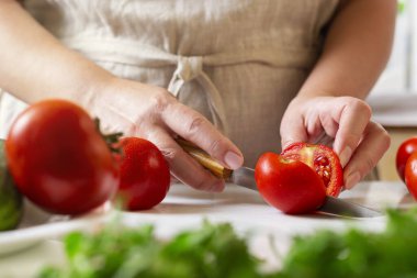 Şef restoranda domatesleri bıçakla dilimliyor. Mutfakta kesim ve hazırlama işlemi.