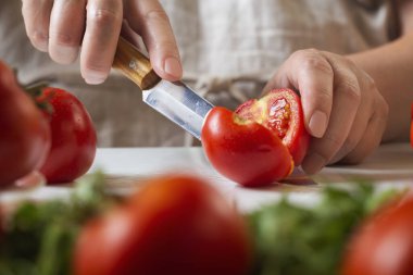 Şef restoranda domatesleri bıçakla dilimliyor. Mutfakta kesim ve hazırlama işlemi.