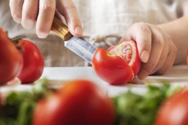 Şef restoranda domatesleri bıçakla dilimliyor. Mutfakta kesim ve hazırlama işlemi.