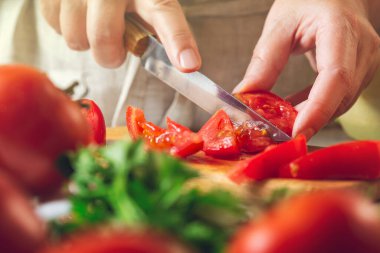 Şef restoranda domatesleri bıçakla dilimliyor. Mutfakta kesim ve hazırlama işlemi.