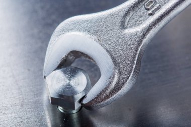 İngiliz anahtarı çelik koğuşta cıvatayı sıkıyor. Anahtar, cıvata, vida ve fındık.