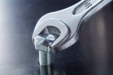 İngiliz anahtarı çelik koğuşta cıvatayı sıkıyor. Anahtar, cıvata, vida ve fındık.