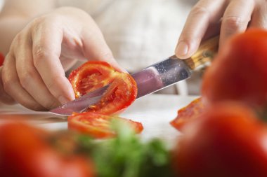 Şef restoranda domatesleri bıçakla dilimliyor. Mutfakta kesim ve hazırlama işlemi.