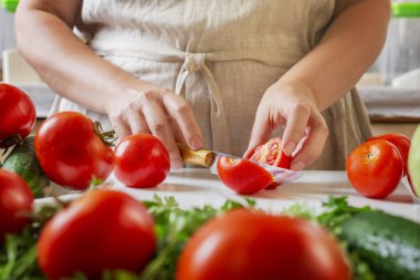 Şef restoranda domatesleri bıçakla dilimliyor. Mutfakta kesim ve hazırlama işlemi.