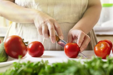 Şef restoranda domatesleri bıçakla dilimliyor. Mutfakta kesim ve hazırlama işlemi.