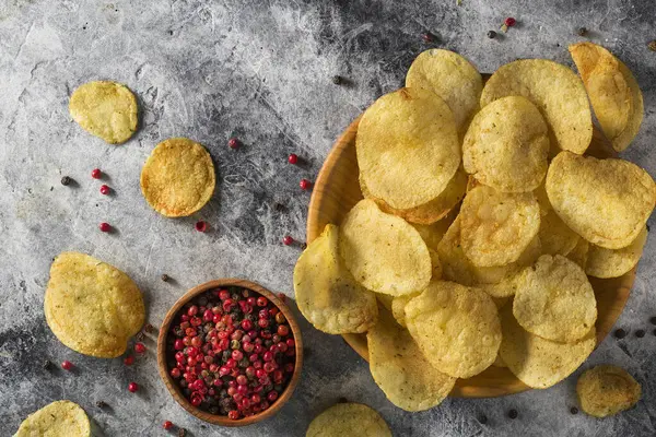 Cips, patates cipsi, sarımsaklı, biberiyeli, gri taşlı arka planda kasede. Abur cubur mu fast food mu?.