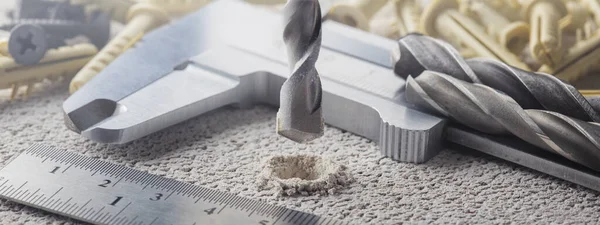 Metal matkap ucu, beton duvarda plastik kaplama ve duvar tıkaçlarıyla delikler açar. Çalışma endüstrisi inşa ediliyor.