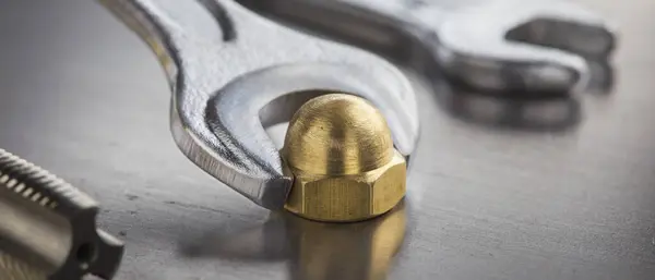 stock image Wrench tightens brass cap nut in steel billet. Spanner, bolt, screw and nuts.