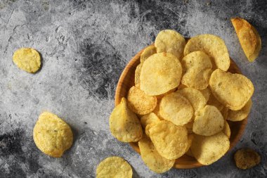 Cips, patates cipsi, sarımsaklı, biberiyeli, gri taşlı arka planda kasede. Abur cubur mu fast food mu?.