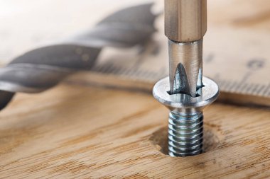 screwdriver screw in a wood oaks plank clipart