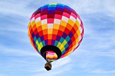 Mavi gökyüzünde beyaz bulutlarla uçan renkli sıcak hava balonu