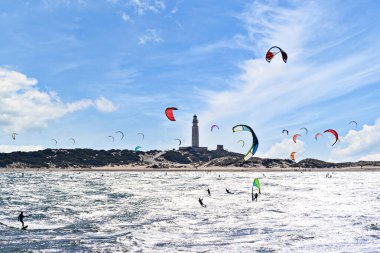 İnsanlar Los Caos de Meca sahilinde uçurtma tatbikatı yapıyor. Trafalgar Deniz Feneri, Barbate, Cdiz 'in yanında.