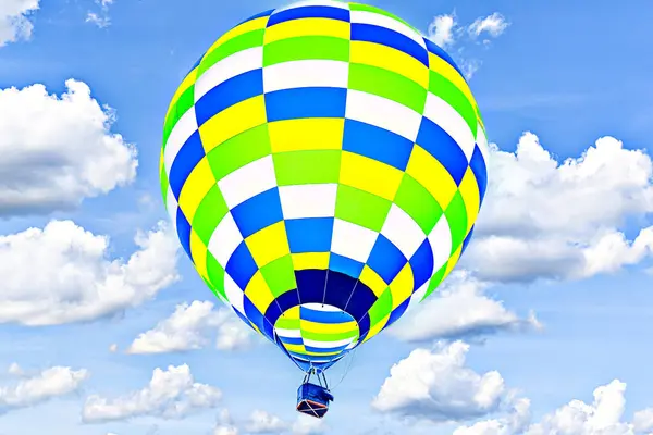 Mavi gökyüzünde beyaz bulutlarla uçan renkli sıcak hava balonu