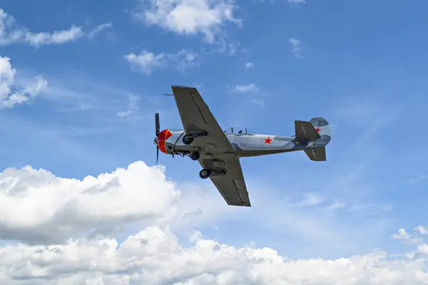 Aerobatik bir uçak (aerodyne), beyaz bulutlu mavi bir gökyüzünün altında uçarken görülüyor. uçuş sergileri