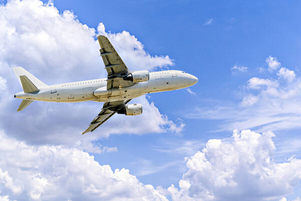 Пассажирский самолет приземляется в аэропорту, под голубым небом с белыми облаками