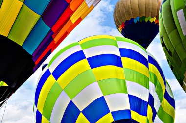 Mavi gökyüzünde beyaz bulutlarla uçan renkli sıcak hava balonu