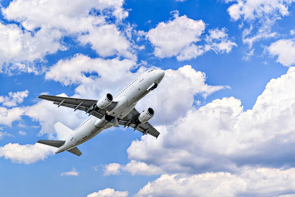 Пассажирский самолет приземляется в аэропорту, под голубым небом с белыми облаками