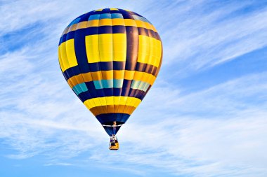 Mavi gökyüzünde beyaz bulutlarla uçan renkli sıcak hava balonu