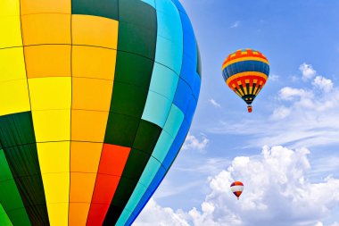 Mavi gökyüzünde beyaz bulutlarla uçan renkli sıcak hava balonu